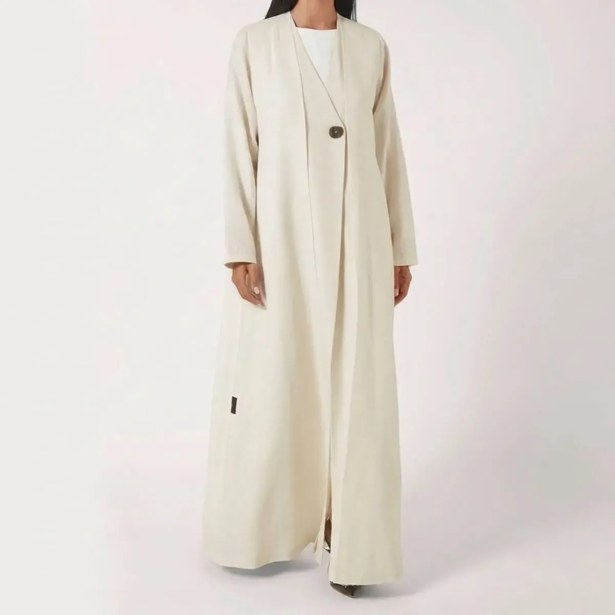 Luxury ivory linen-look abaya featuring a wrap-front silhouette, horn-effect button, full-length flowing design, and minimalist contemporary tailoring by LAYL.